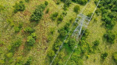 Dağlık arazideki elektrik direkleri ve yüksek voltaj hatları. Yüksek voltaj direkleri. Elektrik iletim güç hatları. 4K, UHD, Sinematik, Hava Görüntüleri