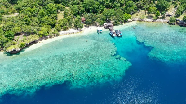 인도네시아의 발리에 있는 망간 섬의 해변 옆에 는 배 한 척 이세워져 있었습니다. 바다에 있는 산호초 위에 배가 세워져 있었습니다. 아름답고 맑은 물. 해변에 나무가 몇 그루있어. 지옥같은 낙원 — 스톡 사진