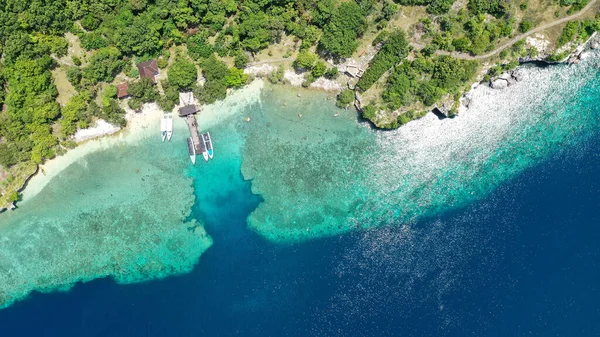 En båt parkerad bredvid stranden på Menjangan Island, Bali, Indonesien. Båtar parkerade på ett korallrev i havet. Vackert och klart vatten. Några träd på stranden. Semester paradis Royaltyfria Stockbilder