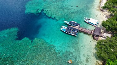 Menjangan adasında mavi denizde iskelede turistik tekneler. Havadan görünüm