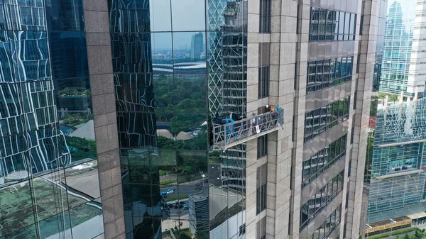 Professional high rise window cleaning service workers in gondola. Two workers use specialized equipment to access and clean windows of skyscraper as preventative maintenance and repair measure