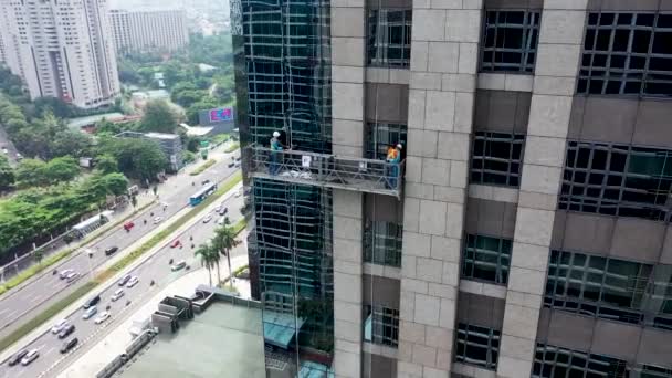 Úklidoví pracovníci pracují na čištění oken z vnějšku výškových budov pomocí gondoly — Stock video