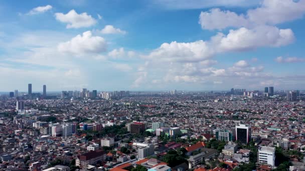 Drone disparo volando sobre edificios de poca altura hacia el horizonte moderno Yakarta, Indonesia urbana — Vídeo de stock