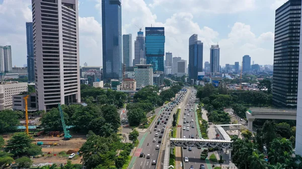 Drone view of quiet traffic on Sudirman road with skyscrapers in Jakarta city.