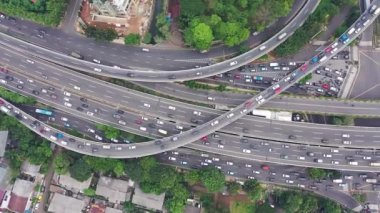 Karmaşık kavşakta yığılmış yol seviyeleri, yukarıdan aşağıya havadan çekim. Büyük, dolambaçlı bir yol ve birçok üst geçit var. Şeritlerde hareketli trafik, kamera aşağı bak ve yukarı kaldır..