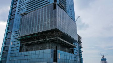 İnşaat halindeki yüksek katlı binaların dış cepheleri. Mavi gökyüzü arka planına sahip gelecekçi ve modern tasarım gökdelen binası. Jakarta 'da çok katlı ofis gökdeleninin inşaatı.