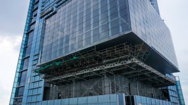 İnşaat halindeki yüksek katlı binaların dış cepheleri. Mavi gökyüzü arka planına sahip gelecekçi ve modern tasarım gökdelen binası. Jakarta 'da çok katlı ofis gökdeleninin inşaatı.
