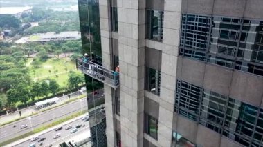 Gondoldaki profesyonel cam temizleme işçileri. İki işçi, önleyici bakım ve onarım tedbiri olarak gökdelenin pencerelerine erişmek ve onları temizlemek için özel ekipman kullanıyor.
