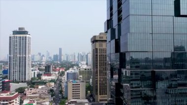 Drone vertical flight among the modern futuristic skyscrapers in Jakarta City business centre, sunset reflection in shiny glass facade.