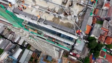 Aerial top down view on the rooftop of an office skyscraper in a course of building under construction with a lot of workers.