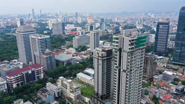 Aerial View of Jakarta Downtown Skyline with High-Rise Buildings With White Clouds and Blue Sky, Indonesia, Asia.