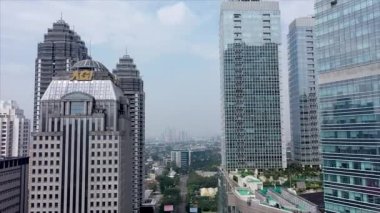 JAKARTA - Indonesia. May 20, 2022: Drone flight over skyscraper windows. Modern office building, aerial view. Cityscape panorama with business center glass facade.