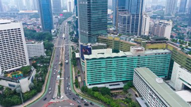 Aerial view of vehicles passing through road with skyscrapers background in Jakarta city.