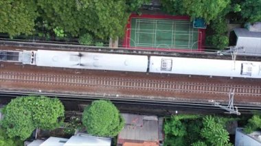 Çerçeveden geçen modern yolcu treni yüksek hızda, yukarıdan aşağıya hava görüntüsü.