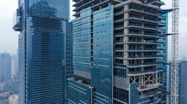 İnşaat sırasında iki gökdelen. Gökdelenler gökyüzüne karşı yapım aşamasında. Cam gökdelenlerin inşaatı. Camla çevrili binalar..