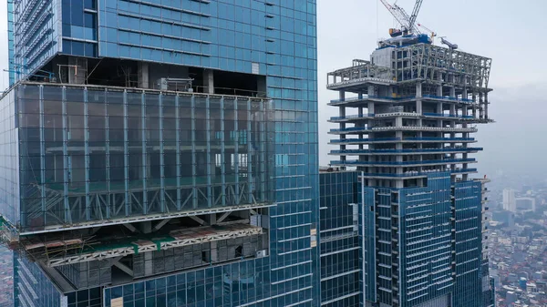 Two skyscrapers during construction. Skyscrapers under construction against the sky. Construction of glass skyscrapers. Facing of buildings with glass.