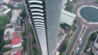 Gökdelenler arasında hareket eden bir hava aracı. Havadaki kuşlar tepeden aşağı Jakarta şehrindeki yüksek binalar arasında yavaşça hareket eden araçların görüntülerini izliyorlar..