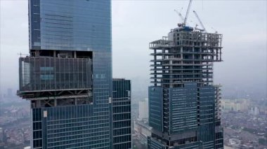 Gökyüzü Uçuşu Yeni Yapılanma Geliştirme Alanında Yüksek Kule Vinçleri Emlak Binası var. Crane, gökdelenleri olan bir inşaat alanında çalışıyor. Çok katlı bir apartmanın inşaatı.