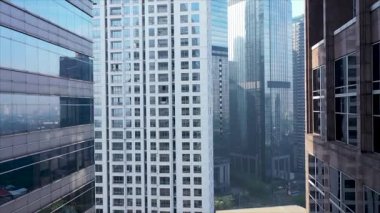 Modern bir şehrin şehir merkezindeki cam gökdelenler arasında geriye doğru uçuyor..