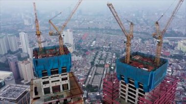 Jakarta, Endonezya 'da inşaat halindeki bir vincin gökdelenin çatısına bir nesneyi indirdiği hava görüntüsünü kapat.