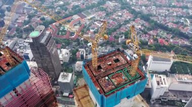 Jakarta, Endonezya 'da inşaat halindeki bir vincin gökdelenin çatısına bir nesneyi indirdiği hava görüntüsünü kapat.