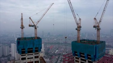 Hava aracı görüntüleri. Yüksek katlı bir apartmanın inşaatı sırasında inşaat alanında çalışan işçiler. Büyük bir şehrin gelişmekte olan bölgesinde yeni yüksek binalar inşa ediliyor..