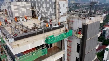 Roof of multistorey building under construction. Modern apartment house builds in the city. Workers build the tower building. Top aerial view.