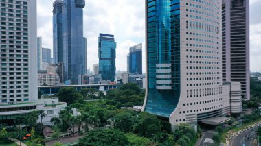 Jakarta şehrinin iş bölgesindeki mavi cam gökdelenli modern gökdelenin havadan görünüşü. Sabahleyin Jakarta şehrinde yüksek binalarla çevrili..