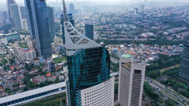 Jakarta şehrinin iş bölgesindeki mavi cam gökdelenli modern gökdelenin havadan görünüşü. Sabahleyin Jakarta şehrinde yüksek binalarla çevrili..
