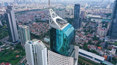 Jakarta şehrinin iş bölgesindeki mavi cam gökdelenli modern gökdelenin havadan görünüşü. Sabahleyin Jakarta şehrinde yüksek binalarla çevrili..