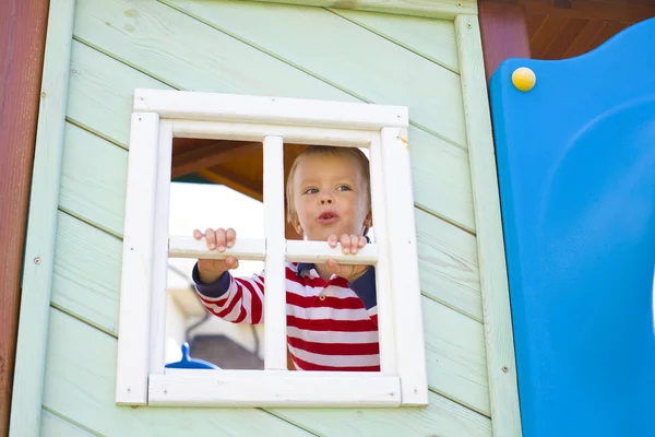 Fyra-åriga pojke som ser ut i ett fönster i ett barns — Stockfoto