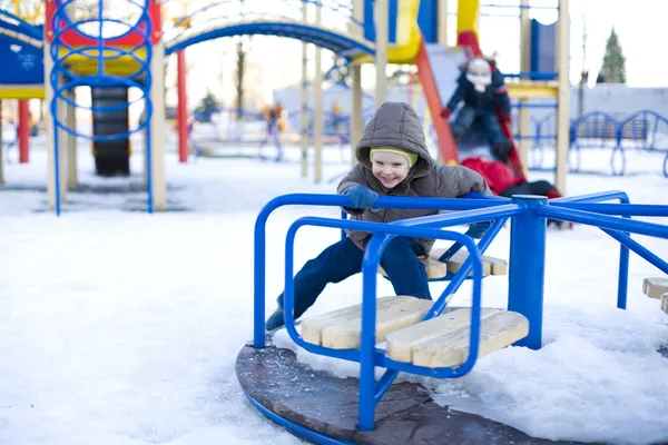 Kleines lachendes Kind fährt im Winter Karussell — Stockfoto