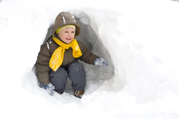 Criança sorridente divertida no inverno em uma caverna de neve — Fotografia de Stock