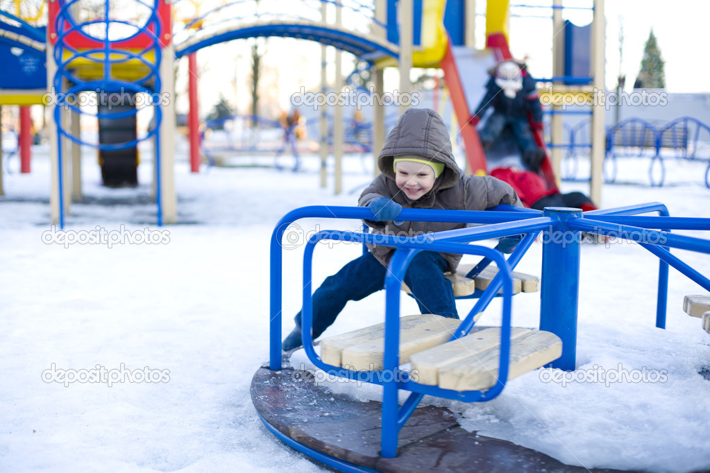 Small laughing child rides carrousel in winter