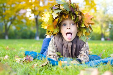 Portrait of cheerful child in a wreath from autumn leaves clipart