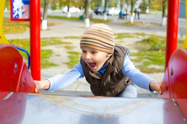 Ativo menino de quatro anos jogando em um playground — Fotografia de Stock