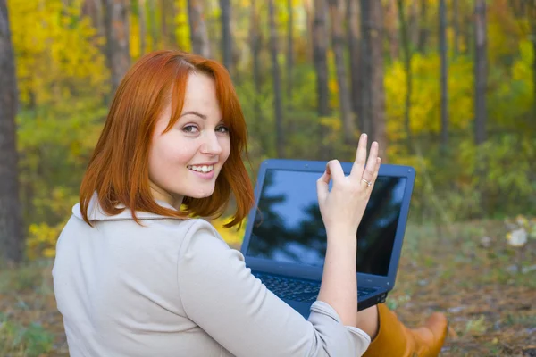 Atrakcyjny rudowłosa dziewczyna z laptopa w drewnie — Zdjęcie stockowe