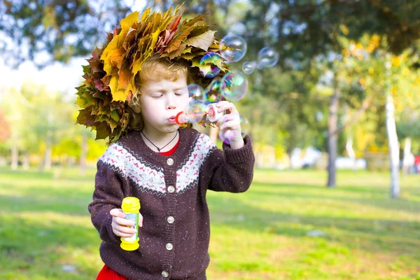 Kleines lustiges Mädchen im Kranz aus Herbstblättern — Stockfoto