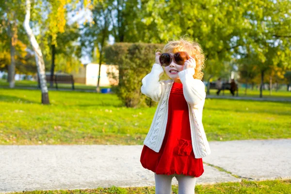 Portrait of a little girl playing in big sunglasses outdoors — Stock Photo, Image