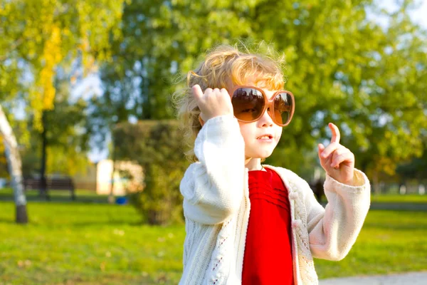 Porträtt av en liten flicka som leker i stora solglasögon utomhus — Stockfoto