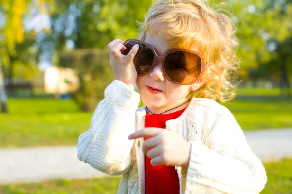 Lächerliches kleines Mädchen setzt große Sonnenbrille auf — Stockfoto