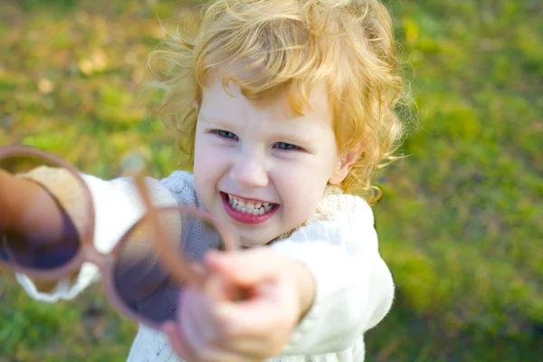 Смешная маленькая девочка надевает большие солнечные очки — стоковое фото