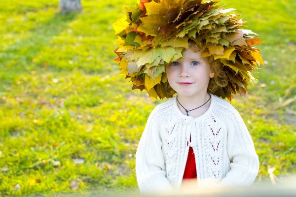 Piccola ragazza divertente in una ghirlanda da foglie di autunno — Foto Stock