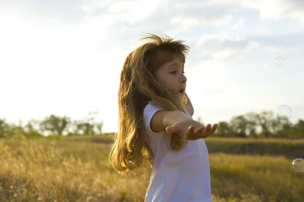 Kleine positieve meisje vangsten zeepbellen — Stockfoto