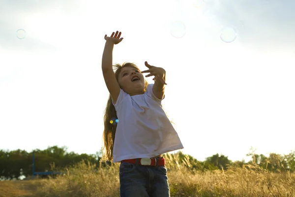 Piccola ragazza positiva cattura bolle di sapone — Foto Stock