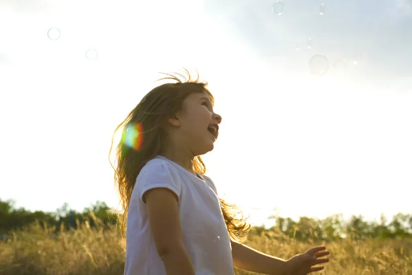 Liten positiv tjej fångster såpbubblor — Stockfoto