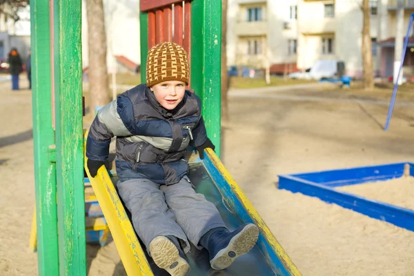 Jongen speelt bij een speelplaats — Stockfoto