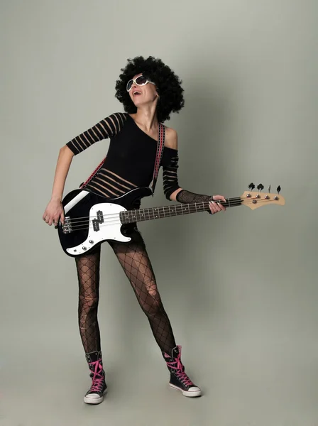 Young cheerful girl in a wig plays on a guitar — Stock Photo, Image