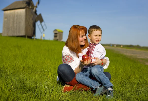 Moeder met kind op een gras in Oekraïense nationale kleding — Stockfoto