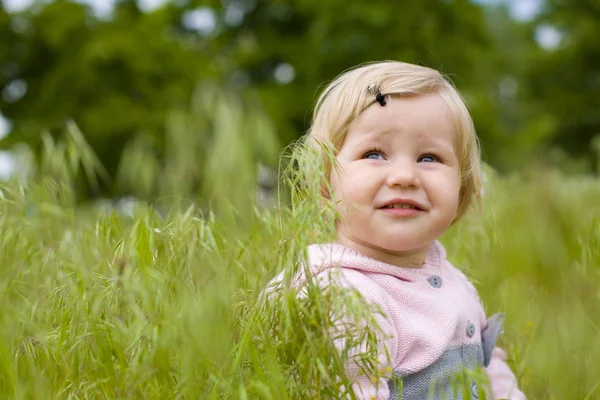 Ritratto della bella bambina seduta su un'erba — Foto Stock